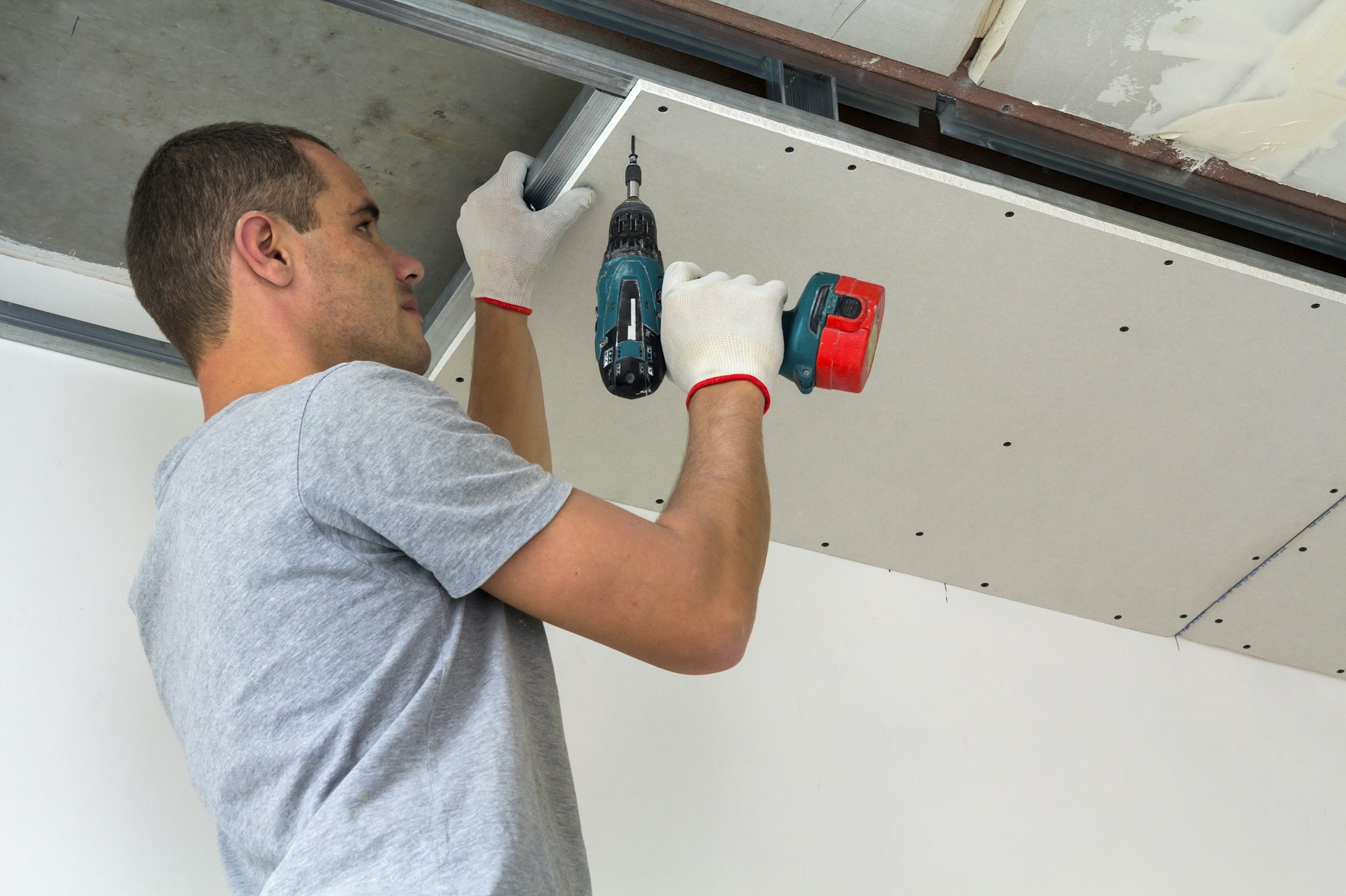 Construction worker assemble a suspended ceiling with drywall and fixing the drywall